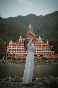A woman in a white dress enjoys a tranquil moment by the famous landmark in Rishikesh, India.