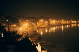 Captivating night scene of Varanasi ghats with glowing lights reflecting on the Ganges River.